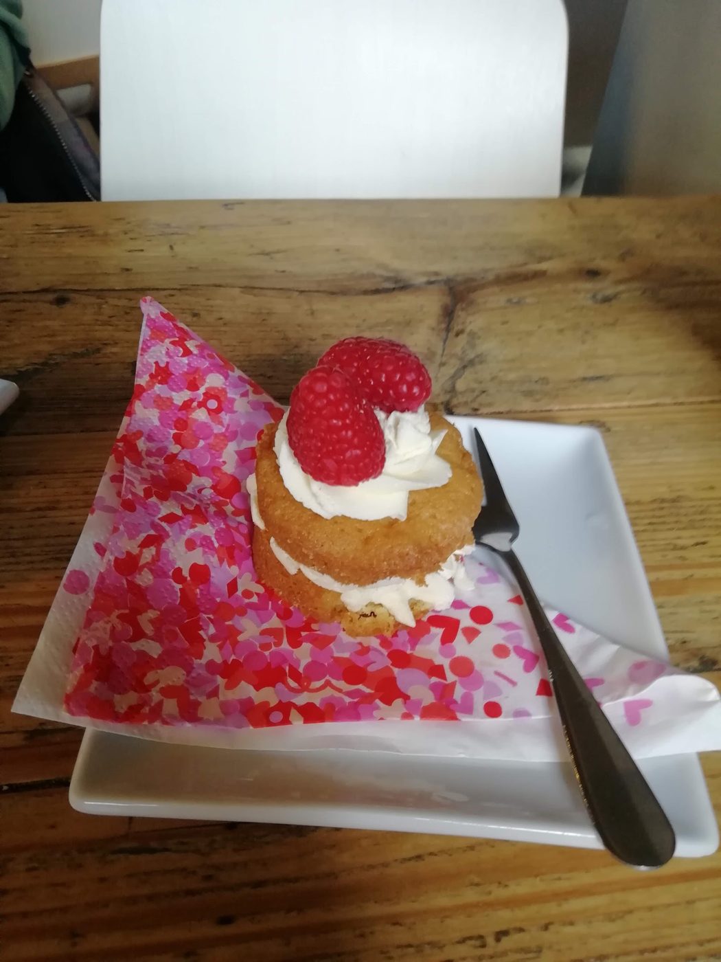 A cake topped with cream and a raspberry