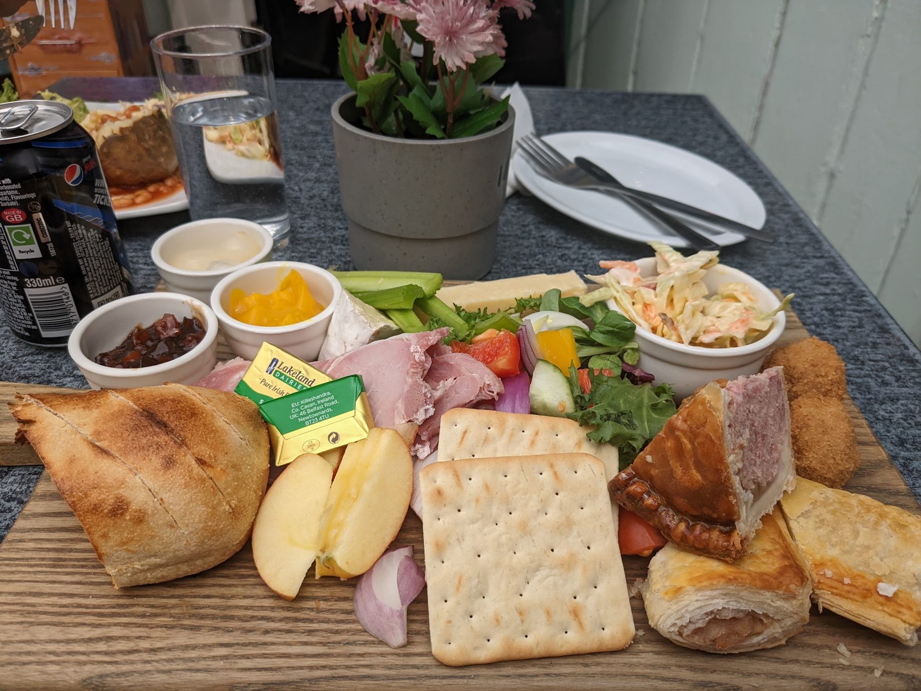 A sharing board with ham, cheese, crackers, bread, apple and chutneys